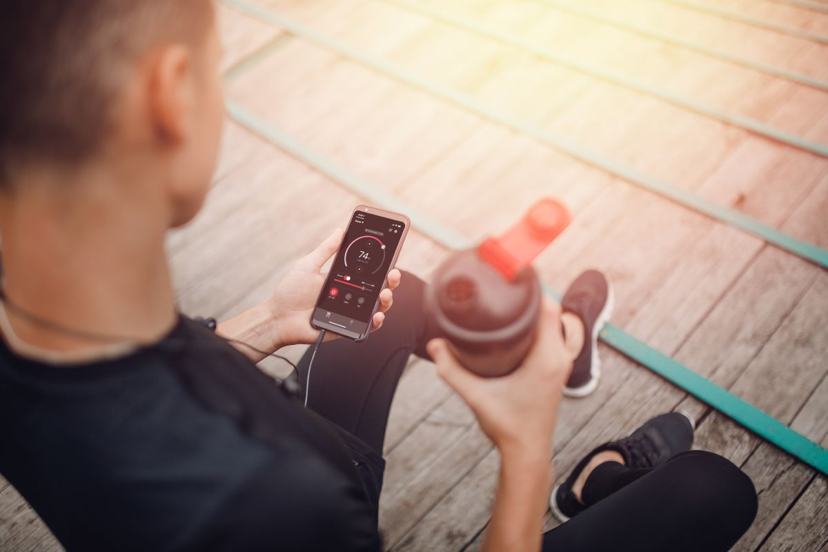 sportists tur ūdens pudeli un telefonu