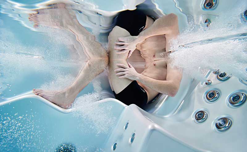 Sieviete atpūšas ergonomiskā atpūtas krēslā USSPA spa baseinā ar darbojas hidromasāžas strūklām